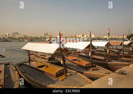 Holzboote, traditionelle Abras als kleine ÖPNV Fähren am Dubai Creek mit Gebäuden im Hintergrund in der Stadt Dubai Stockfoto