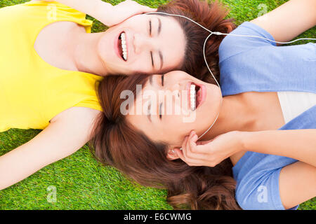 zwei hübsche junge Frau auf der Wiese liegen und Musik hören Stockfoto