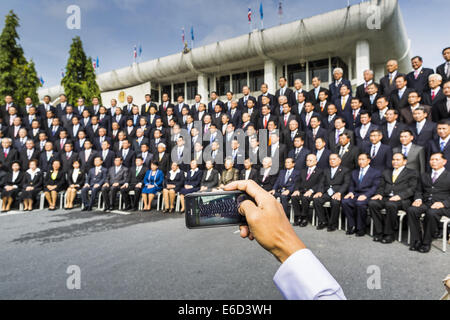 Bangkok, Bangkok, Thailand. 21. August 2014. Eine legislative Mitarbeiterin verwendet ein iPhone, ein Bild der thailändischen nationalen Legislative Assembly (NLA) während ihrer Gruppenfoto Donnerstag im Parlament in Bangkok vor der Auswahl einer neuen Premierminister. Die NLA wurde handverlesenen von Thai Junta, offiziell als der Nationalrat für Frieden und Ordnung (NCPO), und soll um Thailand zurück zu einer Zivilregierung zu führen, nach ein Militärputsch die gewählte Regierung im Mai stürzte. Die NLA wählte einstimmig General Prayuth Chan-Ocha, Kommandant der thailändischen Streitkräfte und Anführer des Staatsstreichs in Mai t Stockfoto