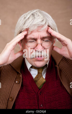 Graue Greis, mit beiden Händen am Kopf. Er hat seine Augen geschlossen, er könnte an Kopfschmerzen leiden. Stockfoto