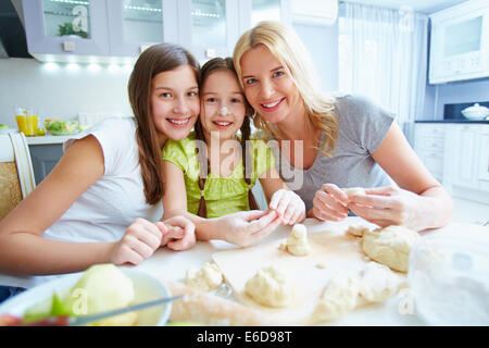 Weibliche Familie lächelnd am Küchentisch Stockfoto