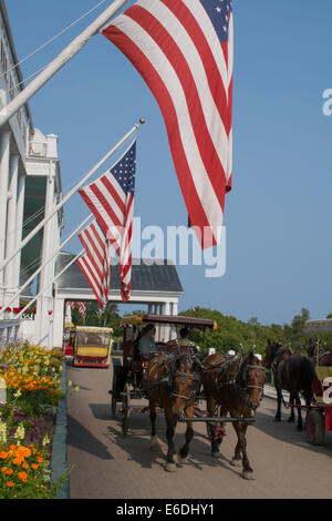 Michigan, Mackinac Island. Historic Grand Hotel Veranda mit uns Fahnen, traditionellen Pferdekutsche. Stockfoto