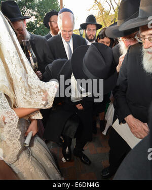 Der Bräutigam bricht ein Glas mit seinem Fuß unter den Chupah bei einer religiösen jüdischen Hochzeit in Crown Heights, Brooklyn, New York. Stockfoto