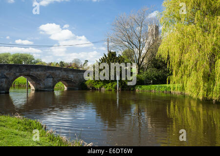 Bogenbrücke über den Fluss Nene in Fotheringhay mit einem Blick auf die beeindruckende Dorf Kirche von Allerheiligen, Northamptonshire, England Stockfoto