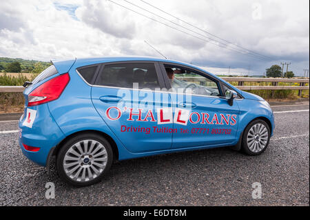 Eine Frau, die eine Fahrstunde in ein fahrendes Auto der Ausbilder im Vereinigten Königreich Stockfoto