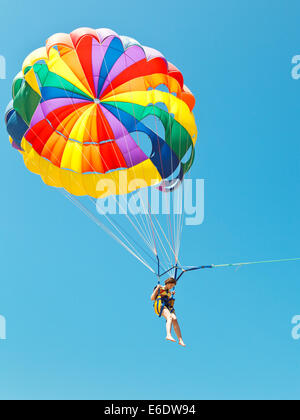 Mädchen-Drachenfliegen am Fallschirm in blauen Himmel im Sommertag Stockfoto