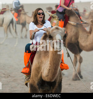 Touristen, Kamelreiten auf berühmte Shan, Dunhuang, Jiuquan, Provinz Gansu, China Stockfoto