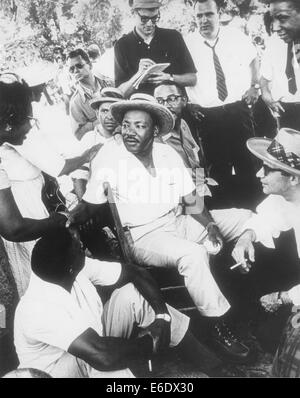 Martin Luther King, Jr. in Strohhut, setzen Sie sich mit einer Gruppe von Männern beim Händeschütteln mit Frau, ca. 1960 Stockfoto