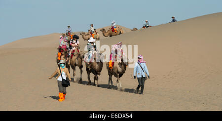 Touristen, Kamelreiten auf berühmte Shan, Dunhuang, Jiuquan, Provinz Gansu, China Stockfoto