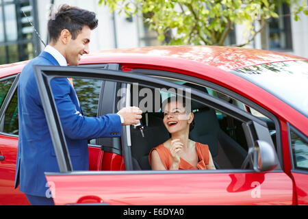 Verkäufer, die die Schlüssel zu einer attraktiven Womans Neuwagen Stockfoto