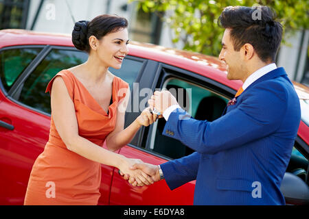 Verkäufer, die die Schlüssel zu einer attraktiven Womans Neuwagen Stockfoto