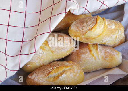 knackig frisch gebackene Brötchen und Brot eingewickelt auf Tischdecke Stockfoto