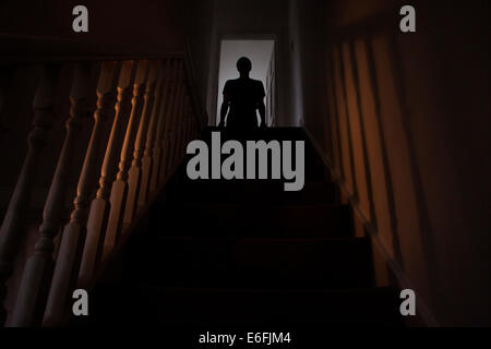 Silhouette eines Mannes stehen an der Spitze einer Treppe, Schatten an den Wänden des Lichts unter. Stockfoto