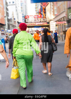Kurvige Frau in Grün Hosen Outfit mit anderen Fußgängern in Times Square Gegend, NYC Stockfoto