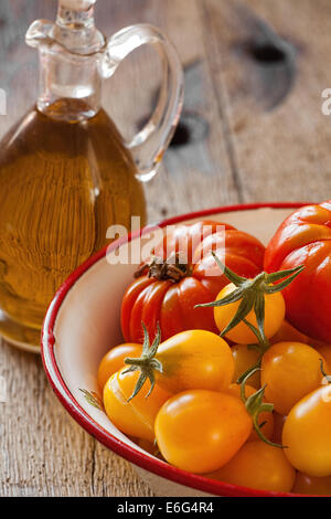 Frisch gepflückten Tomaten in einem Emaille Schüssel Fleisch und eine Flasche Olivenöl Stockfoto