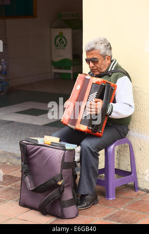 BANOS, ECUADOR - 28. Februar 2014: Unbekannter Mann Akkordeon zu spielen, am Eingang der Markthalle in Ambato Straße Stockfoto