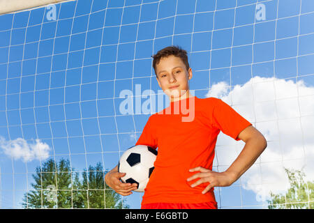 Fröhlicher Junge in orange T-shirt mit Fußball Stockfoto