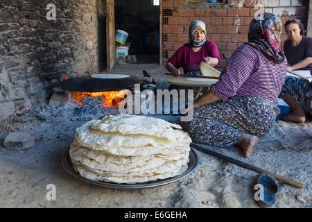 EVRENLERYAVSI, Türkei - 24. Juni 2014: Dorffrauen bereiten traditionelle Fladenbrot am offenen Feuer. Stockfoto