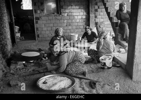 EVRENLERYAVSI, Türkei - 24. Juni 2014: Dorffrauen bereiten traditionelle Fladenbrot am offenen Feuer. Schwarz / weiß Stockfoto