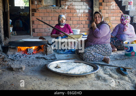 EVRENLERYAVSI, Türkei - 24. Juni 2014: Dorffrauen bereiten traditionelle Fladenbrot am offenen Feuer. Stockfoto