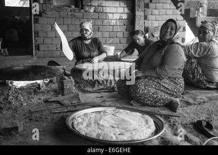 EVRENLERYAVSI, Türkei - 24. Juni 2014: Dorffrauen bereiten traditionelle Fladenbrot am offenen Feuer. Schwarz / weiß Stockfoto