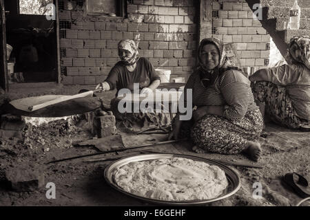 EVRENLERYAVSI, Türkei - 24. Juni 2014: Dorffrauen bereiten traditionelle Fladenbrot am offenen Feuer. Sepia Stockfoto