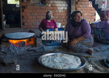 EVRENLERYAVSI, Türkei - 24. Juni 2014: Dorffrauen bereiten traditionelle Fladenbrot am offenen Feuer. Stockfoto