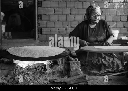 EVRENLERYAVSI, Türkei - 24. Juni 2014: Dorffrauen bereiten traditionelle Fladenbrot am offenen Feuer. Schwarz und weiß. Fokus auf th Stockfoto