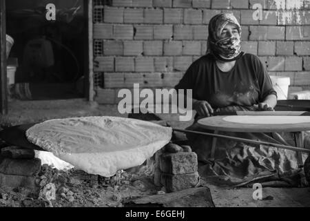 EVRENLERYAVSI, Türkei - 24. Juni 2014: Dorffrauen bereiten traditionelle Fladenbrot am offenen Feuer. Schwarz und weiß. Fokus auf th Stockfoto