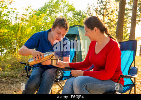 Man gießt heißen Tee von einer Frau, Thermoskanne Stockfoto