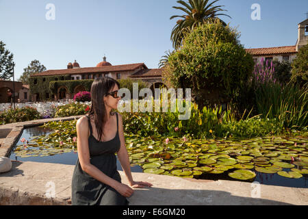 Weibliche asiatische sitzen durch den Seerosenteich im Innenhof von der Mission San Juan Capistrano, Kalifornien, USA Stockfoto