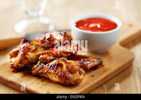 Hähnchenflügel mit Sriracha Sauce auf Holztisch Stockfoto