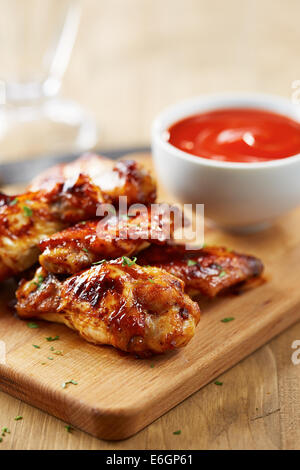 Hähnchenflügel mit Sriracha Sauce auf Holztisch Stockfoto