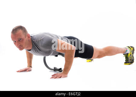 Junge blonde muskulöser Mann Training auf dem Boden mit Pilates Ring isoliert auf weiss Stockfoto