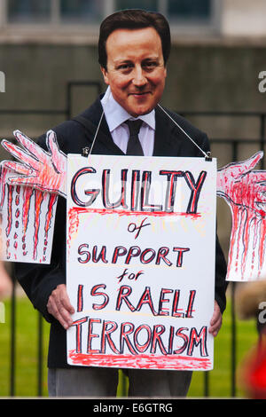 London, UK. 23. August 2014. Ein Demonstrator trägt eine Maske von David Cameron und verkündet seine Schuld für Unterstützung Israels, wie Hunderte von Pro-palästinensischen Demonstranten zeigen außen Downing Street fordern, dass Großbritannien stoppt Israel Bewaffnung. Bildnachweis: Paul Davey/Alamy Live-Nachrichten Stockfoto
