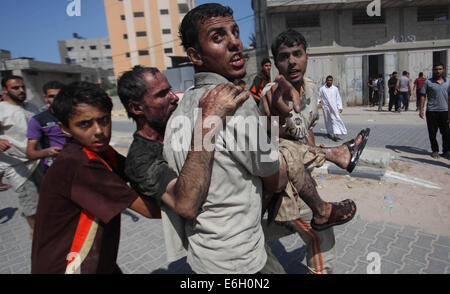 Gaza-Stadt, Gazastreifen, Palästinensische Gebiete. 23. August 2014. Palästinensische Männer bewegen einen verwundeten Mann von einem israelischen Militärschlag auf Ziel in Gaza-Stadt am 23. August 2014 Credit: Ashraf Amra/APA Bilder/ZUMA Draht/Alamy Live News Stockfoto