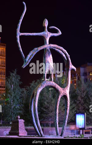 eine Nachtansicht einer Bronzestatue in Pseudo-primitiven Stil mit einem Mitfahrer auf Reiten rückwärts mit einem Bogen schießen Stockfoto