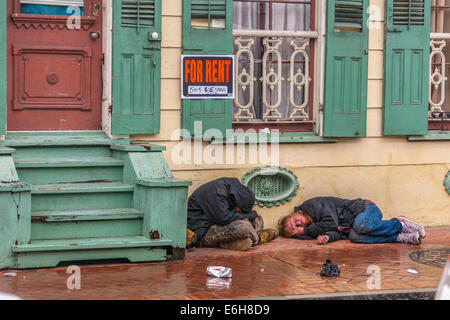 Männer schlafen auf dem Bürgersteig in der Regen nach einer Nacht im French Quarter von New Orleans, Louisiana Stockfoto