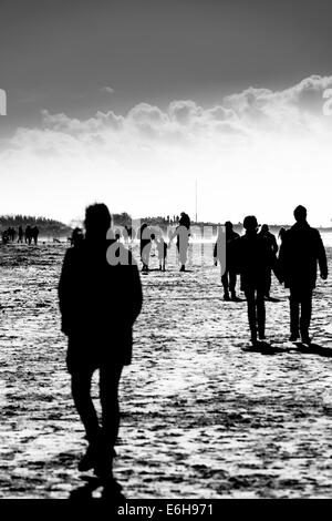 Silhouetten von Personen, die einen Winter-Spaziergang am Strand Stockfoto