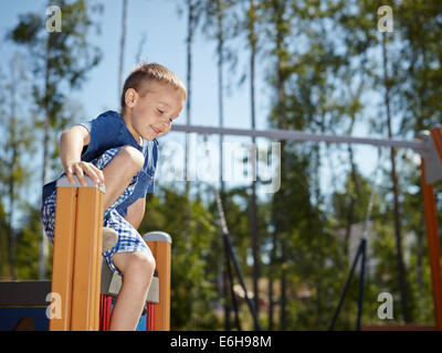 Sechs Jahre alter Junge Klettern am Spielplatz Stockfoto