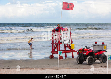 Bademeister wacht über junge spielt mit Skim Board in der Brandung in Daytona Beach, Florida Stockfoto