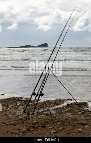 Angeln auf Wolfsbarsch auf Rhossili Strand in Gower mit Wurmkopf am Horizont Stockfoto