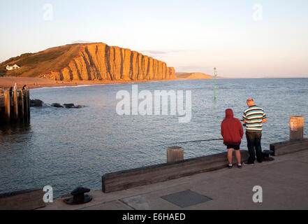 Goldene Abendlicht auf Ost Klippen, West Bay, Bridport, Dorset, England mit Vater und Sohn Angeln im Vordergrund Stockfoto