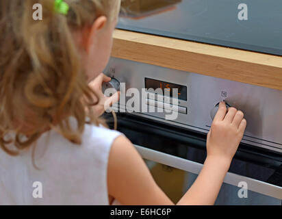 Gefährliche Situation in der Küche. Kind spielt mit Elektro-Backofen. Stockfoto