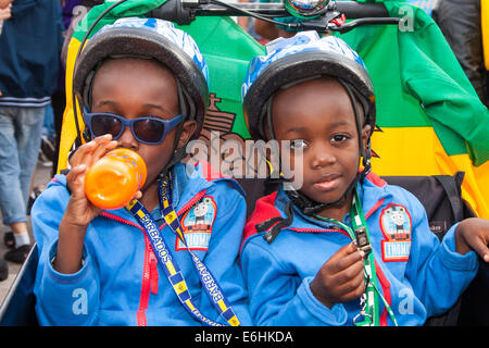 London, UK. 24. August 2014. Zwei Kleinkinder beobachten Sie Verfahren, wie Tausende von Londonern aller Rassen und Kulturen besuchen Notting Hill Carnival 'Familienfreundlich' Tag vor dem wichtigsten Karneval am August Bank Holiday Montag. Bildnachweis: Paul Davey/Alamy Live-Nachrichten Stockfoto