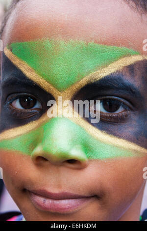 London, UK. 24. August 2014. Ein Junge, sein Gesicht gemalt in den Farben der jamaikanische Flagge, blickt in die Kamera, wie Tausende von Londonern aller Rassen und Kulturen Notting Hill Carnival 'Familienfreundlich' Tag vor dem wichtigsten Karneval am August Bank Holiday Montag besuchen. Bildnachweis: Paul Davey/Alamy Live-Nachrichten Stockfoto