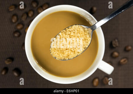 Brauner Zucker auf einem Löffel und einer Tasse Kaffee unter Stockfoto