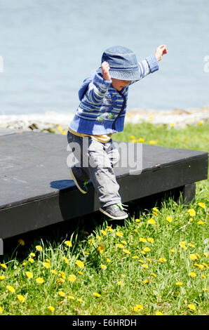 Ein kleiner Junge aus einer hölzernen Plattform springen Stockfoto