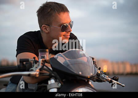 Romantische Porträt schöner Biker Mann mit Sonnenbrille sitzt auf einem Fahrrad Stockfoto