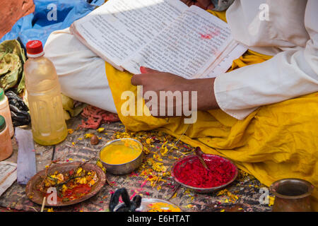 Ein Hindupriester, tragen traditionellen Kleidung, Durchführung ein religiöses Ritual auf einem Markt in Kathmandu, Nepal. Stockfoto